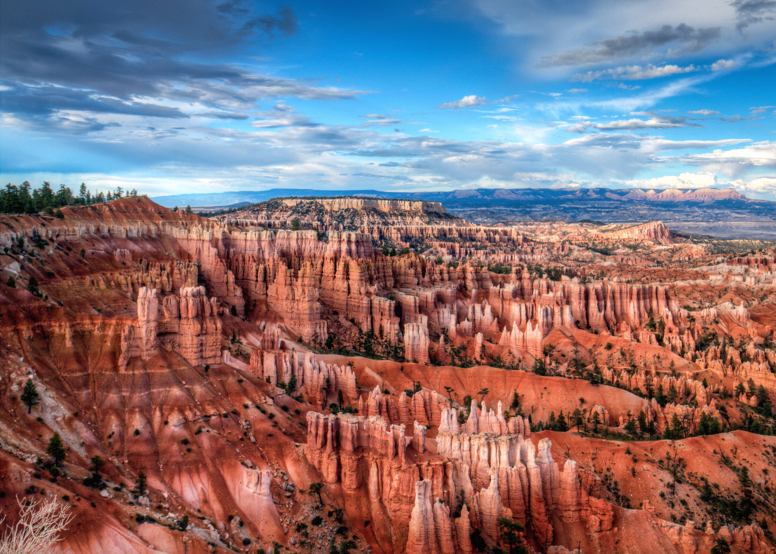 A breathtaking view of red rock formations and hoodoos under a partly cloudy sky, symbolising ongoing but invisible change.